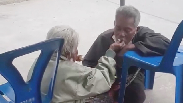 노이 아이마사트(81세)가 그의 아들 참니안(62세)에게 밥을 먹여주고 있다. 이들은 정부가 주는 코로나 보조금을 받기 위해 자정부터 은행 앞에서 줄을 서 있었다. (사진 : 폰 던 카몬팁의 페이스북)